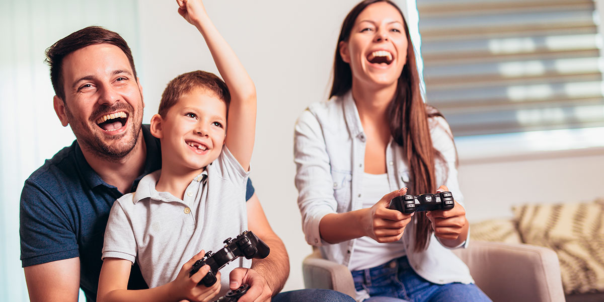 Young family laughing while playing video games.