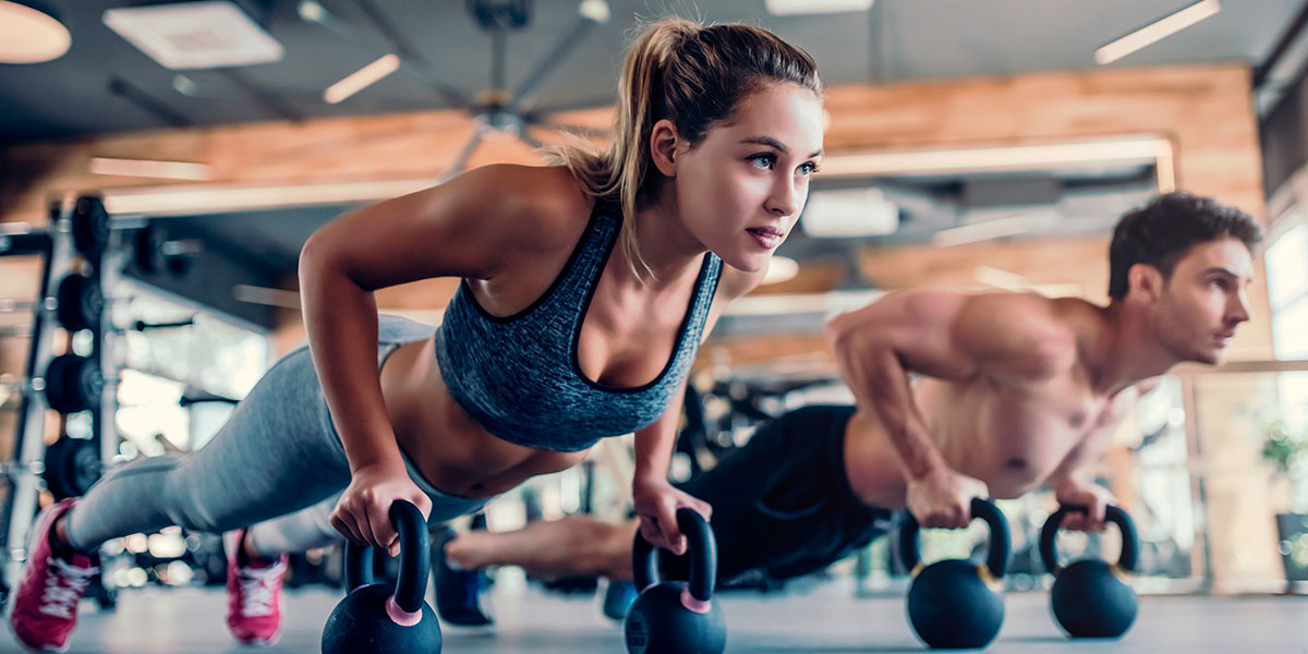 Woman and man doing pushups on kettlebells