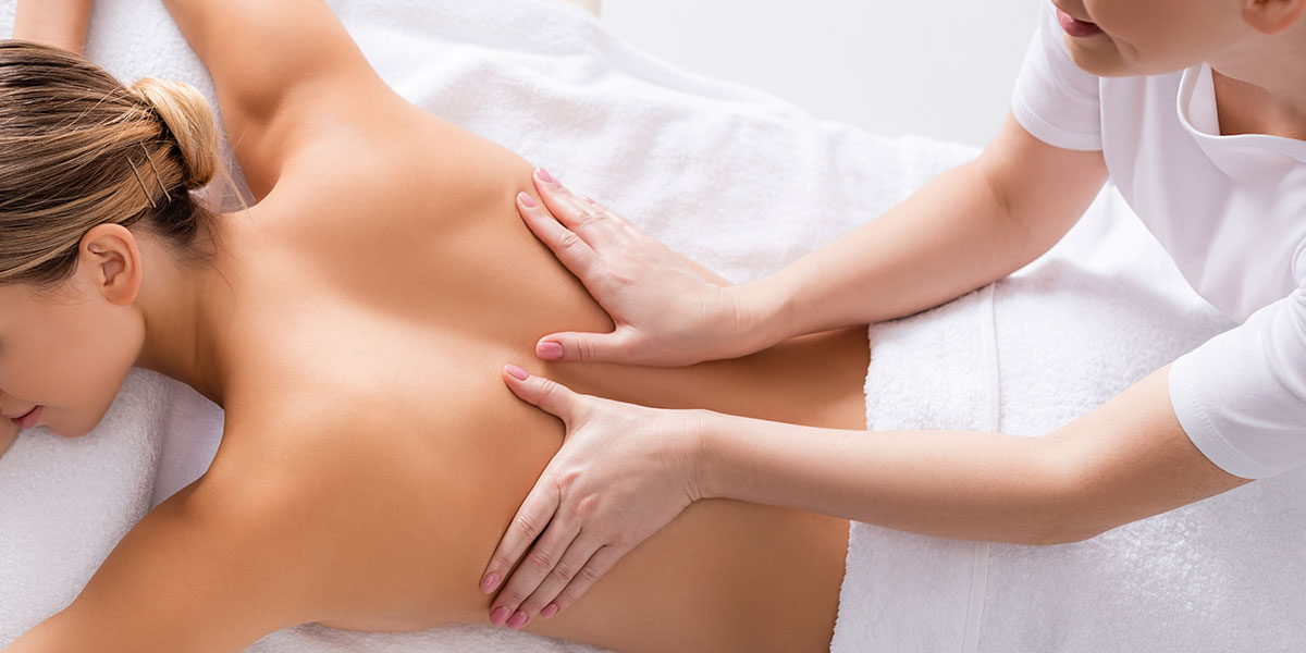 Woman laying on her stomach getting her back massaged.