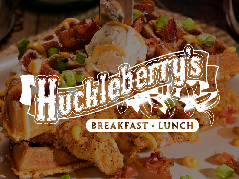 Huckleberry's logo over an image of Chicken and waffles topped with bacon.