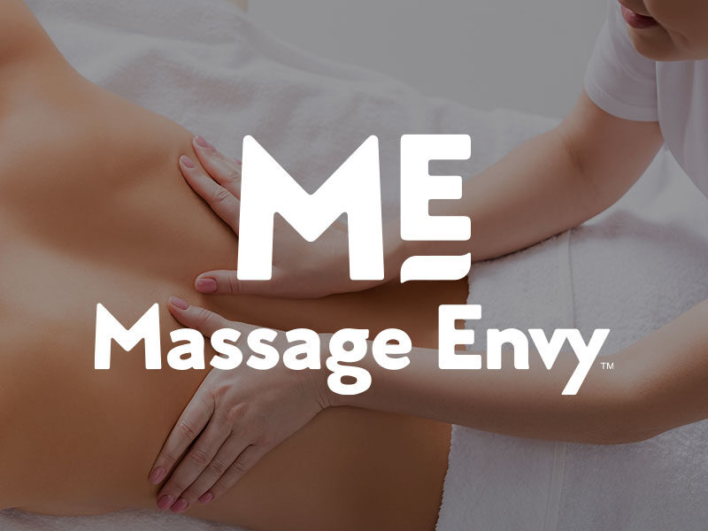 Massage Envy logo over an image of a Woman laying on her stomach getting her back massaged.