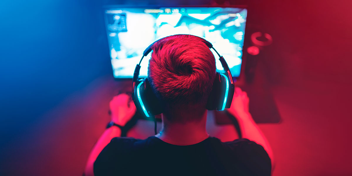 Guy with headphones playing games on a computer screen.