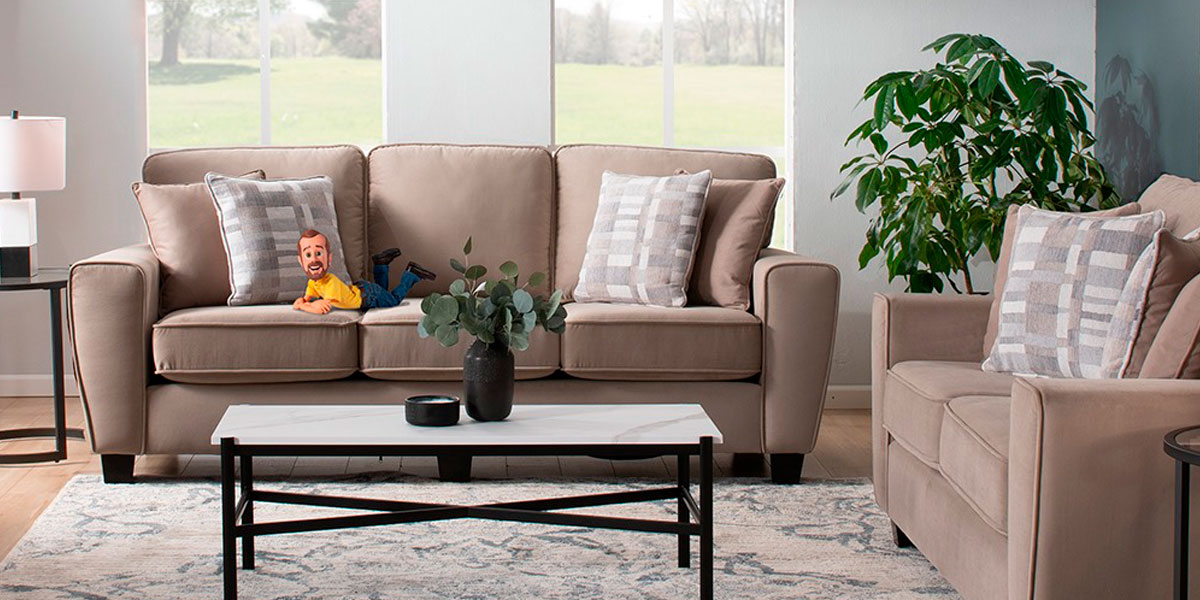 Bob's Furniture puppet mascot laying on a brown sofa
