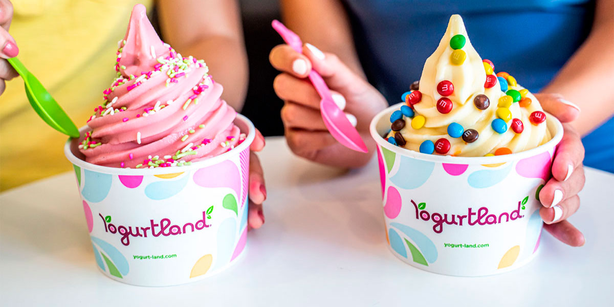 One large pink frozen yogurt covered in sprinkles and one large vanilla frozen yogurt covered in M&M's from Yogurtland.