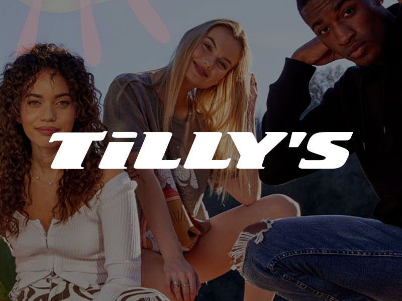Tilly's logo over an image of Four stylish teenagers sitting and kneeling outdoors under the sun.